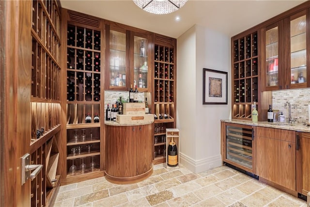 wine room with baseboards, recessed lighting, stone tile flooring, a sink, and wine cooler