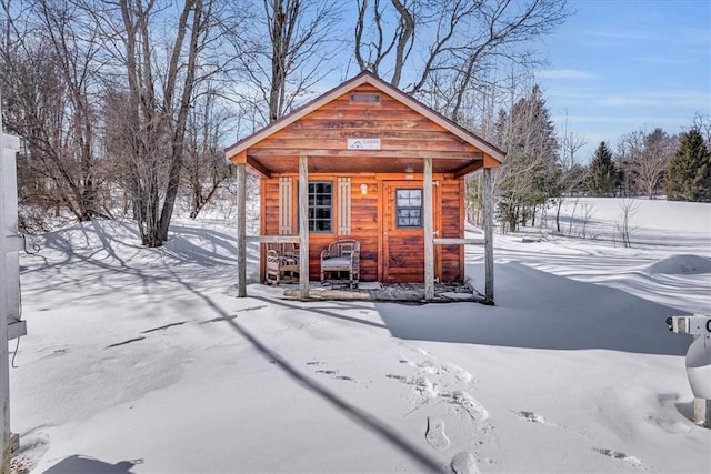 snow covered structure featuring an outbuilding and fence