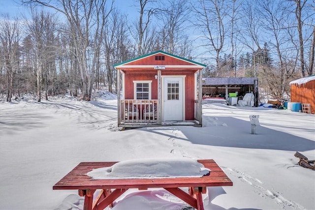 snow covered structure featuring an outbuilding