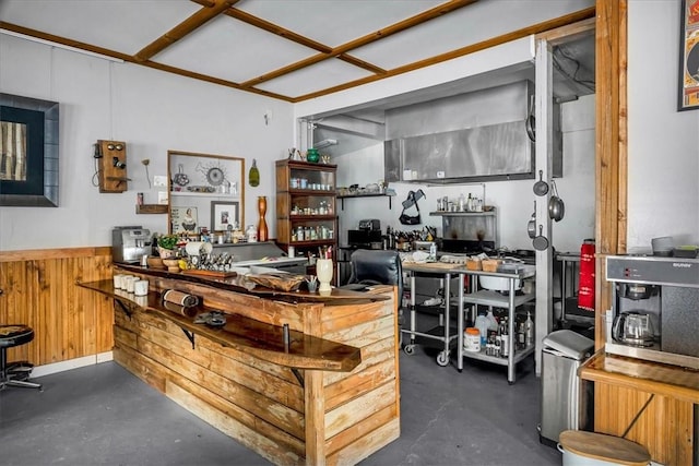 interior space featuring a wainscoted wall, a bar, concrete flooring, and wood walls