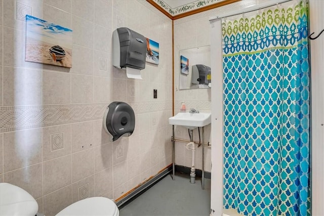 bathroom with curtained shower, tile walls, toilet, and a sink