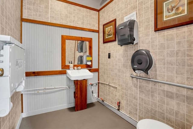 half bath featuring concrete floors, vanity, toilet, and tile walls
