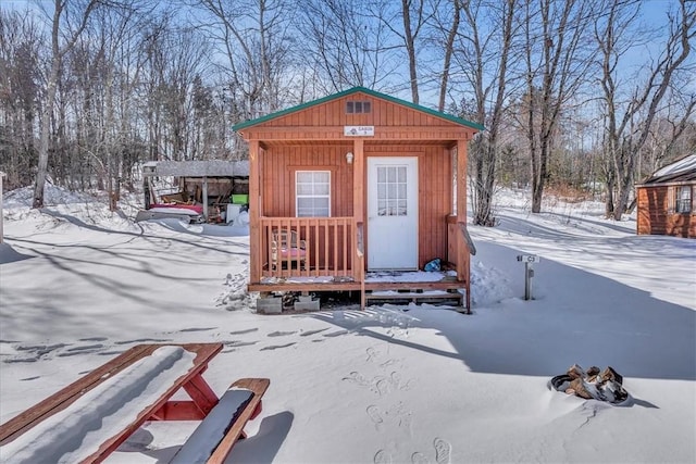 snow covered structure featuring an outbuilding