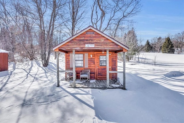 snow covered structure with an outbuilding and fence