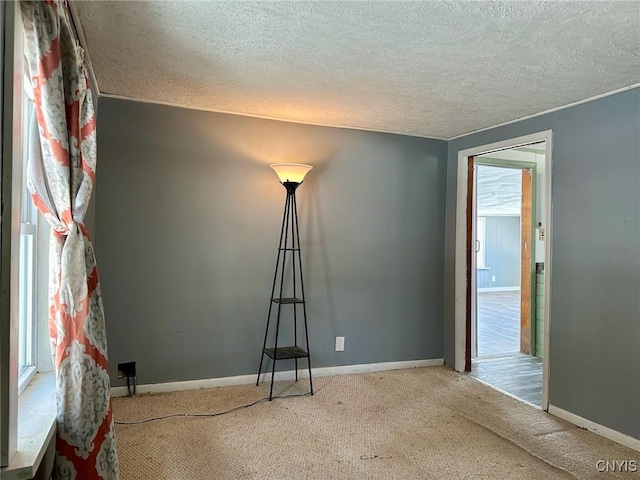 spare room featuring baseboards, carpet floors, and a textured ceiling