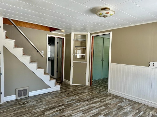 spare room featuring visible vents, stairs, a wainscoted wall, and wood finished floors