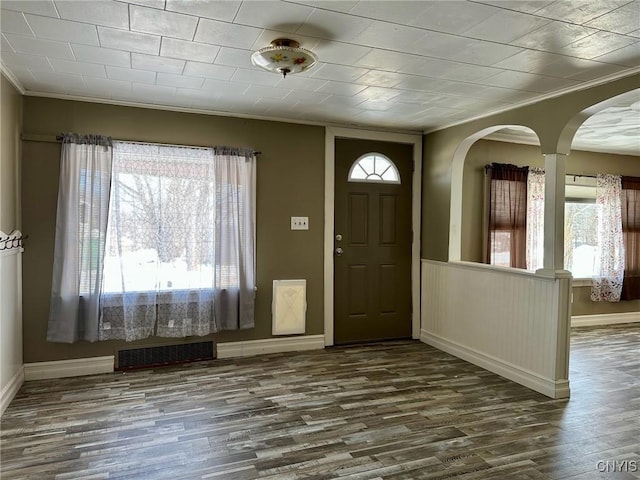 foyer entrance featuring dark wood-style floors, visible vents, crown molding, and baseboards