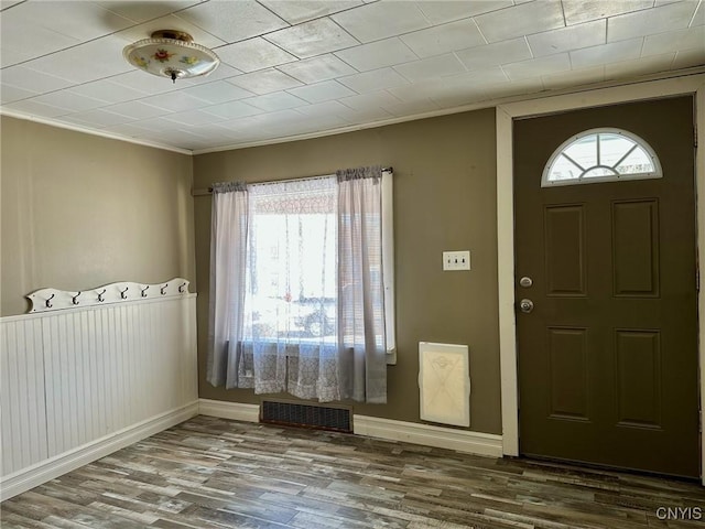 entrance foyer featuring visible vents, baseboards, wood finished floors, and crown molding