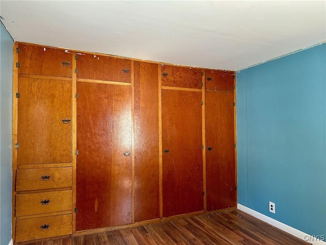 unfurnished bedroom featuring wood finished floors, a closet, and baseboards