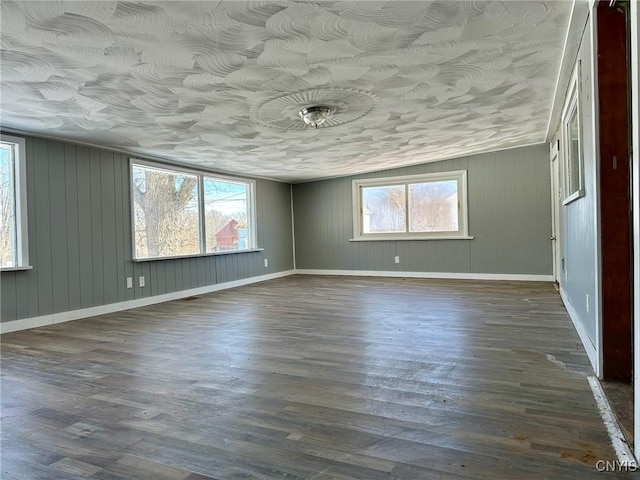 unfurnished room with a wealth of natural light, baseboards, and dark wood finished floors