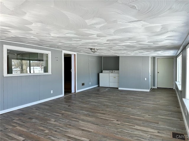 interior space featuring dark wood-style floors, visible vents, baseboards, and washing machine and clothes dryer