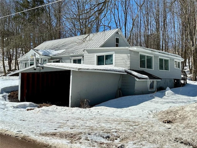 snow covered property with a standing seam roof, a garage, and metal roof