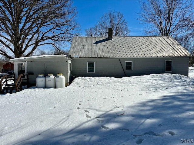 view of snowy exterior with metal roof and an outdoor structure