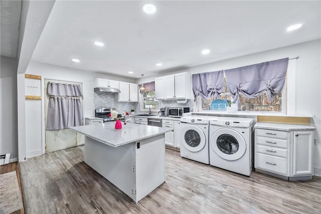 kitchen with light wood-type flooring, a sink, tasteful backsplash, separate washer and dryer, and appliances with stainless steel finishes