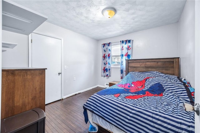 bedroom featuring baseboards, wood-type flooring, and a textured ceiling