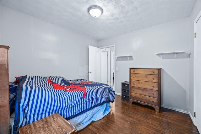 bedroom featuring a textured ceiling, baseboards, and wood finished floors