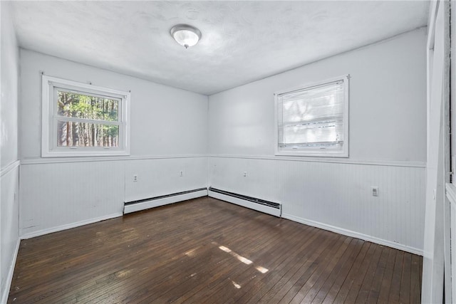 unfurnished room featuring a wainscoted wall, baseboard heating, and wood-type flooring