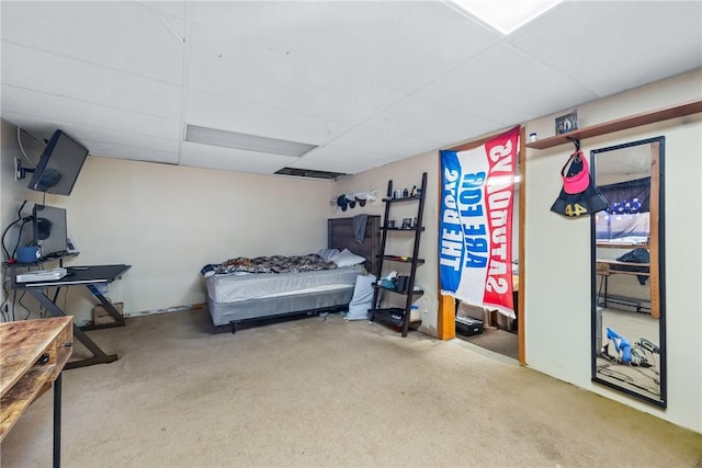 carpeted bedroom featuring a drop ceiling