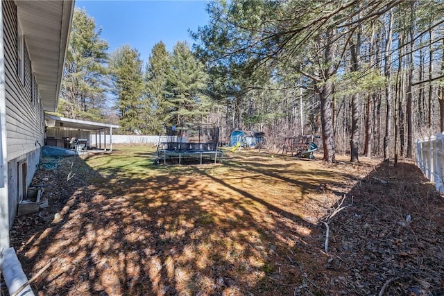 view of yard with fence, a trampoline, and a playground