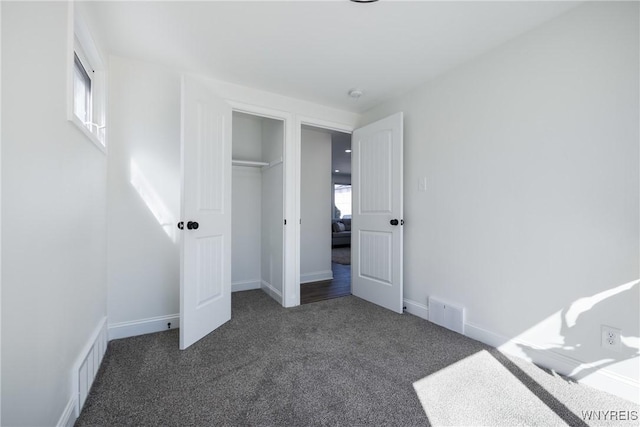 unfurnished bedroom featuring carpet flooring, multiple windows, baseboards, and visible vents