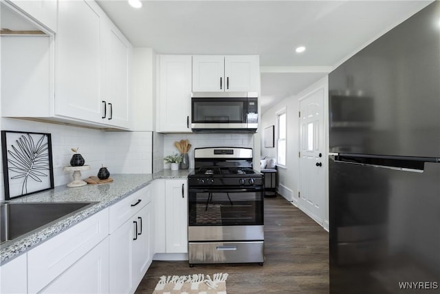 kitchen with light stone counters, tasteful backsplash, dark wood-style floors, white cabinetry, and stainless steel appliances