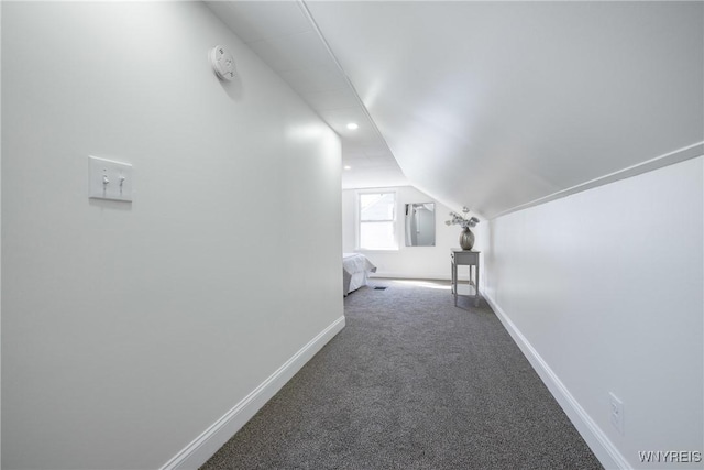 corridor with baseboards, carpet, and vaulted ceiling