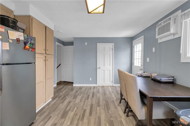 dining space with baseboards, light wood-style floors, an AC wall unit, and a textured ceiling