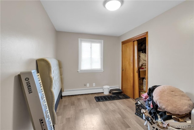 interior space with a baseboard radiator, baseboards, and wood finished floors