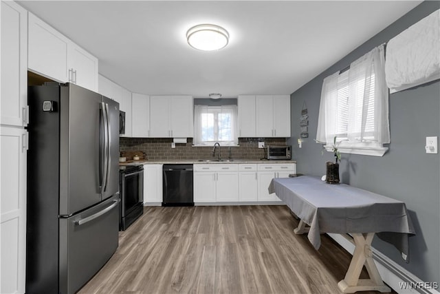 kitchen featuring decorative backsplash, black appliances, white cabinetry, and a sink