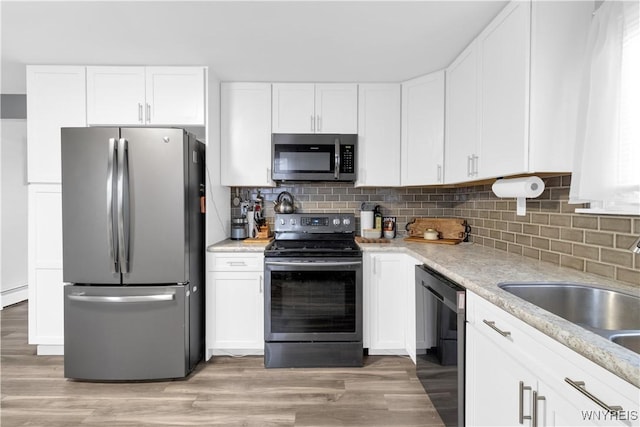 kitchen with a sink, white cabinets, backsplash, and stainless steel appliances