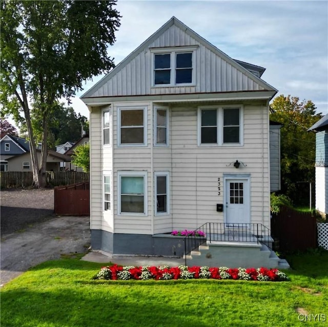 back of property featuring a lawn, board and batten siding, and fence