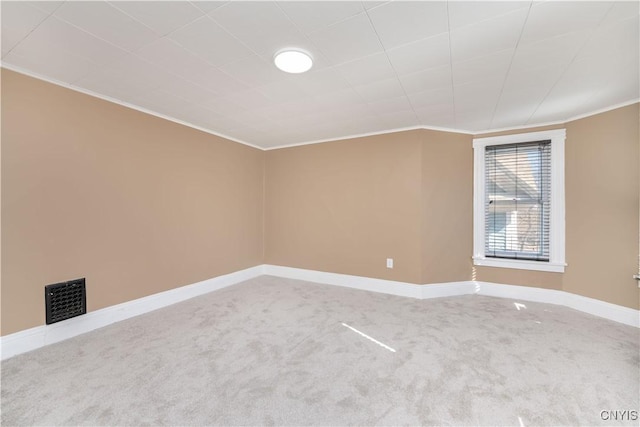 carpeted empty room with visible vents, baseboards, and ornamental molding