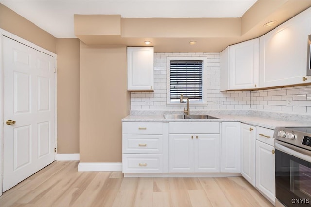 kitchen with backsplash, stainless steel electric range oven, light wood-style floors, and a sink