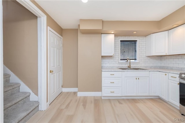 kitchen featuring a sink, tasteful backsplash, white cabinets, and light wood finished floors