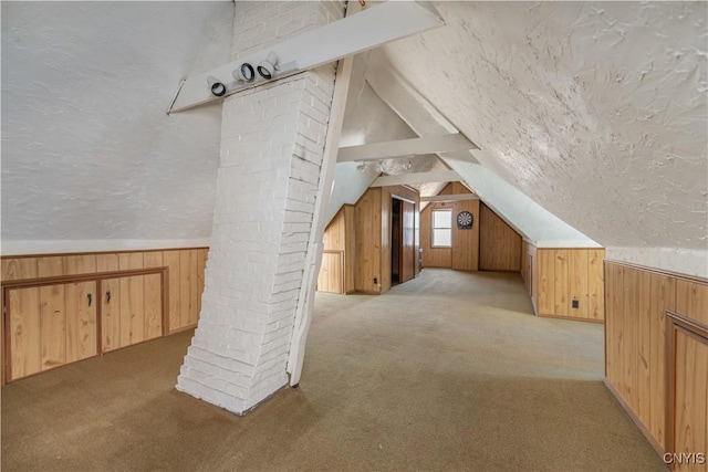 additional living space with light colored carpet, lofted ceiling, wooden walls, and a textured ceiling