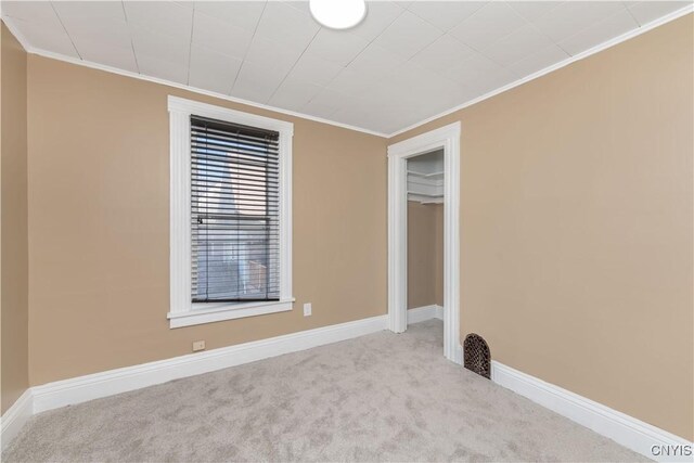 carpeted empty room featuring baseboards and crown molding