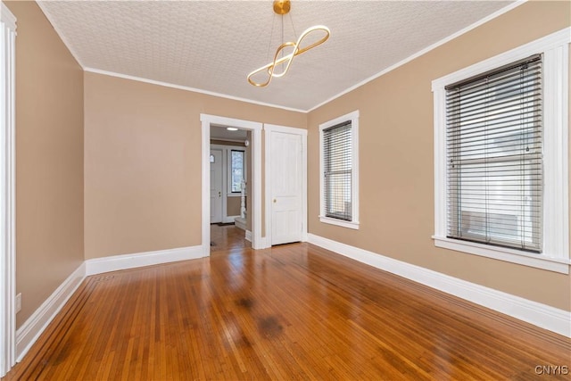 unfurnished room featuring baseboards, a healthy amount of sunlight, crown molding, and hardwood / wood-style flooring