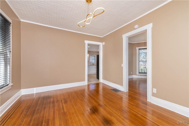 empty room featuring hardwood / wood-style floors, baseboards, and ornamental molding