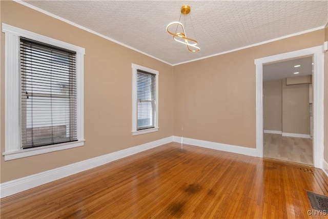 spare room with visible vents, wood finished floors, and ornamental molding