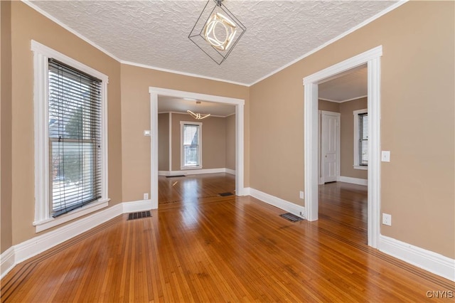 spare room featuring visible vents, wood-type flooring, a textured ceiling, and crown molding