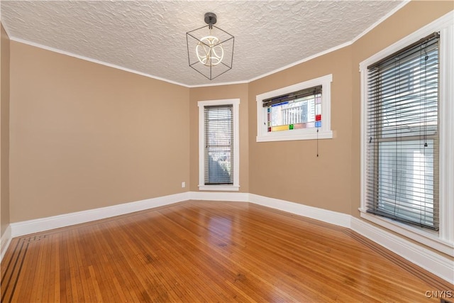 unfurnished room featuring baseboards, light wood-style floors, crown molding, and a textured ceiling