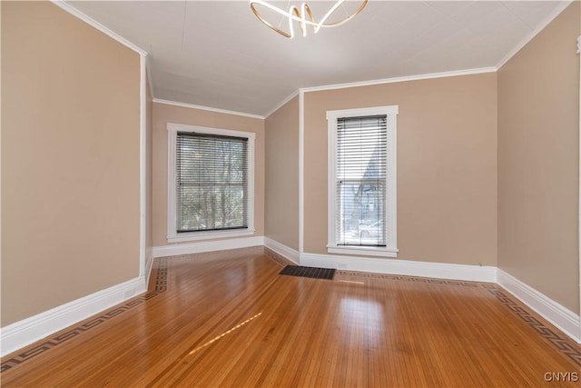 spare room featuring crown molding, baseboards, and wood finished floors