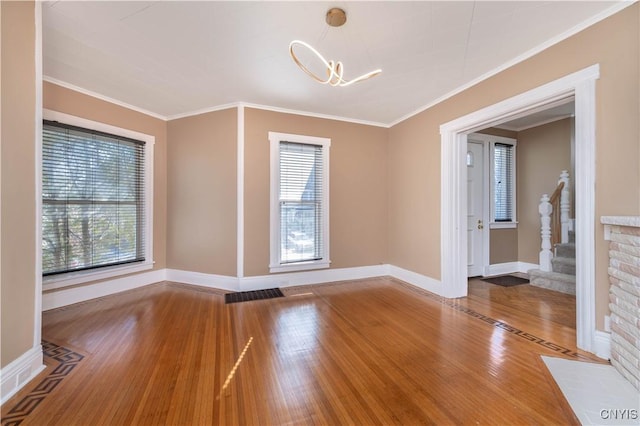 empty room featuring plenty of natural light, wood finished floors, and crown molding