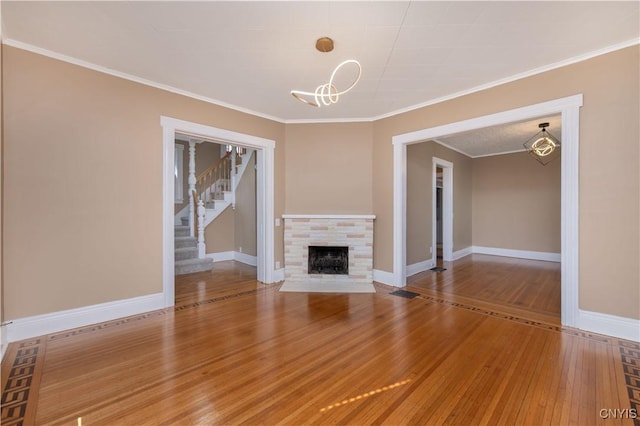 unfurnished living room featuring stairs, wood finished floors, baseboards, and a tile fireplace