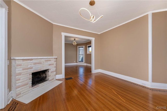 unfurnished living room featuring a brick fireplace, baseboards, a chandelier, ornamental molding, and hardwood / wood-style floors