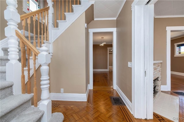 entrance foyer featuring visible vents, a fireplace with flush hearth, crown molding, and baseboards