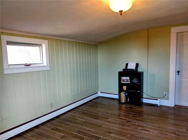 empty room featuring dark wood-type flooring and baseboard heating