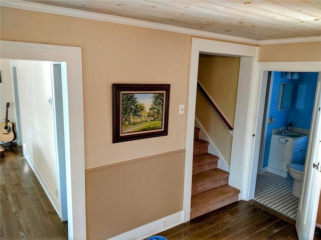 corridor with dark wood-type flooring, ornamental molding, a sink, stairway, and wood ceiling