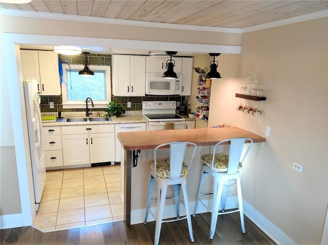 kitchen with ornamental molding, a sink, white appliances, white cabinets, and decorative backsplash