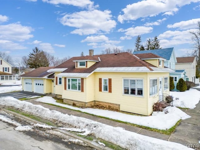 bungalow with a garage, a chimney, and aphalt driveway